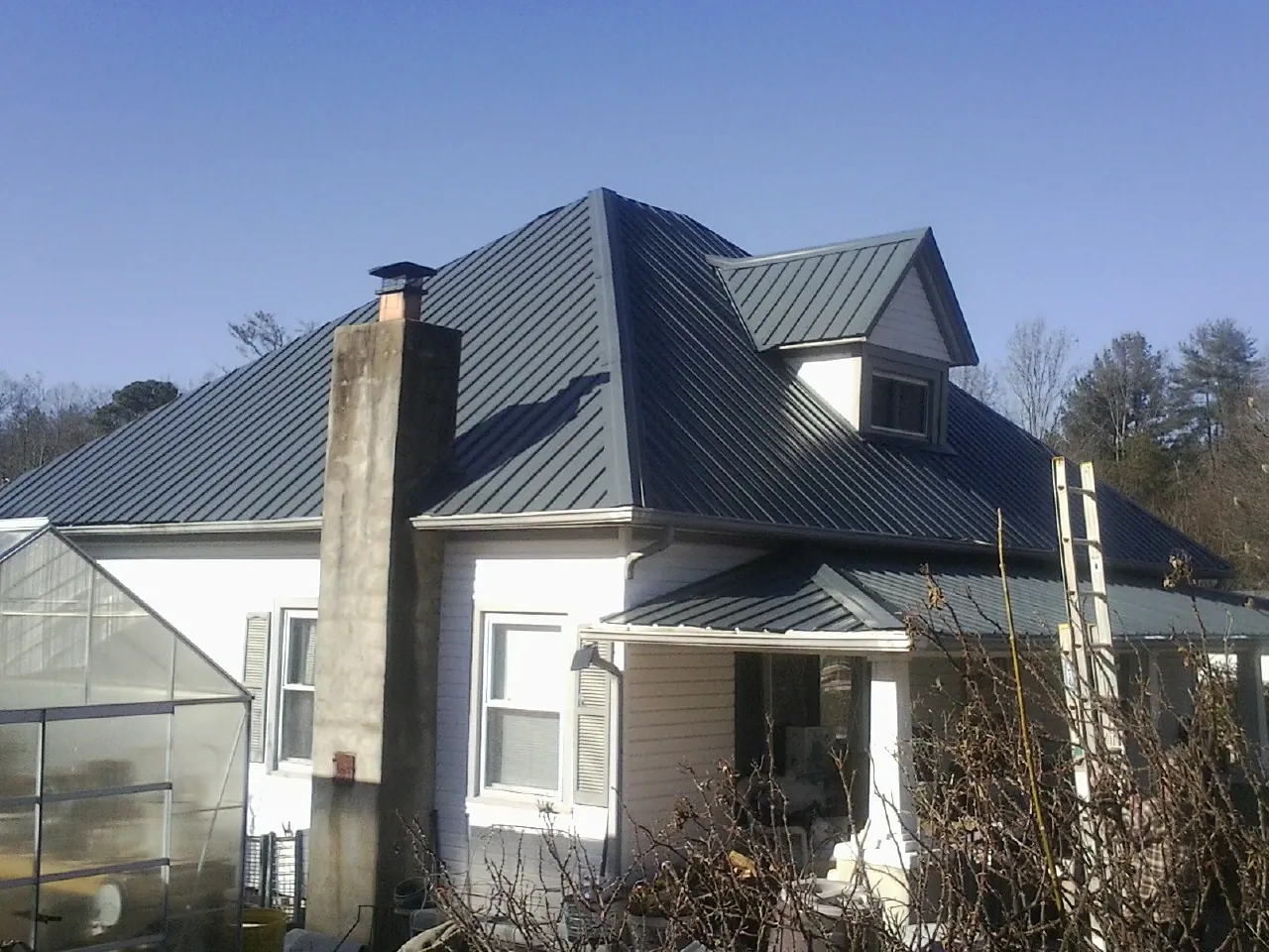 Dark blue standing seam metal roof on a white farmhouse with dormer — Slate & Tile Roof Repair by Roofing Brothers in Dixie