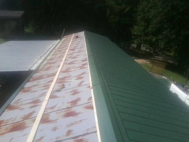 Old rusted panels beside newly installed green metal roofing — Wind Damage Roof Repair by Roofing Brothers in Dixie