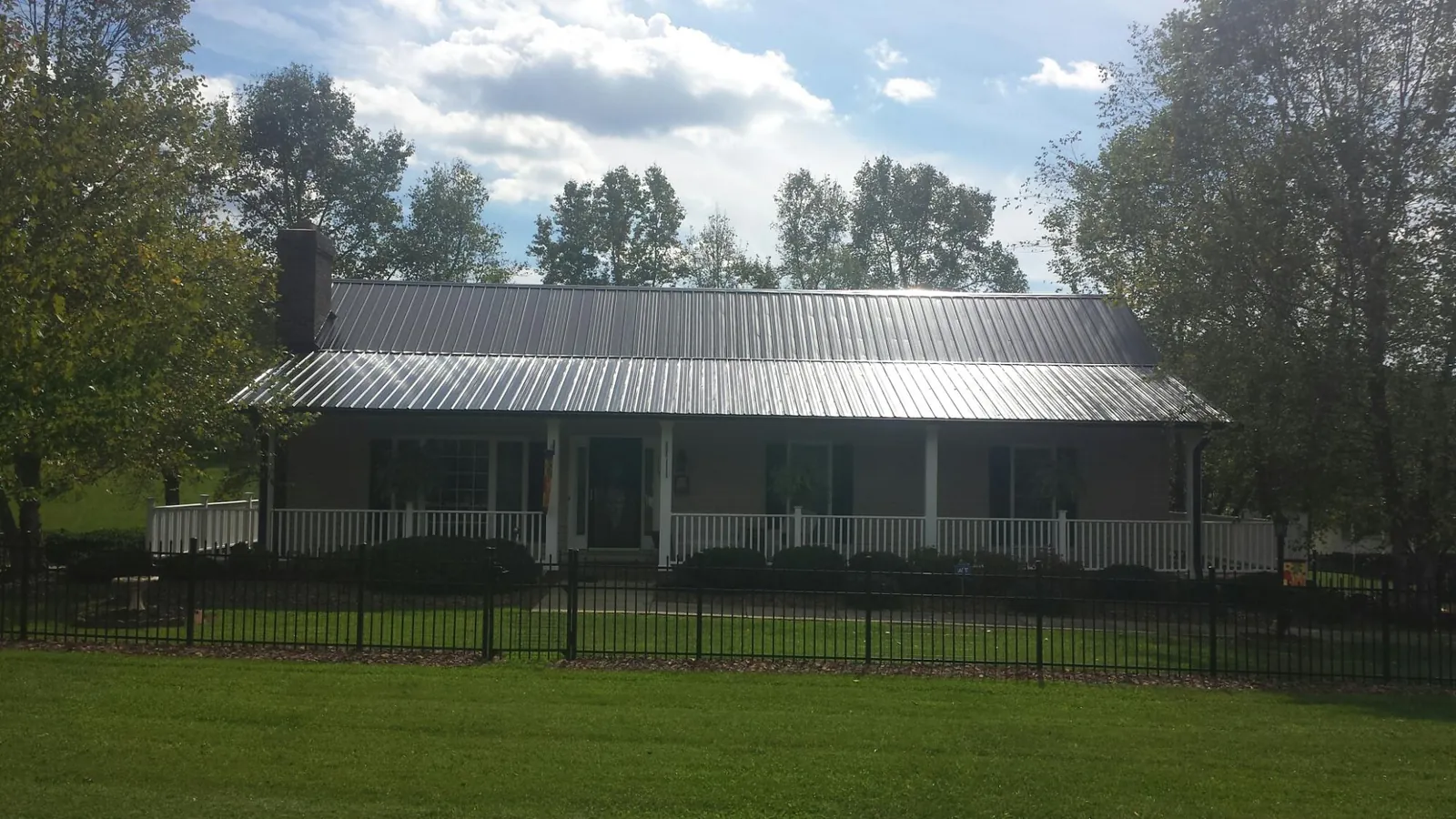 Gray metal roof on a brick ranch with a full width front porch — Gutter Guard Installation work by our crew in Dixie
